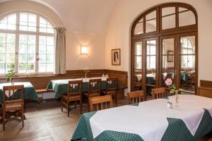 a restaurant with tables and chairs and windows at Gutshotel Odelzhausen in Odelzhausen