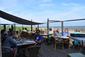 a group of people sitting at tables on a deck at Mobilehome Super Mercure 2 Bedrooms Comfort Camping Scheldeoord in Baarland