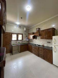 a large kitchen with wooden cabinets and a refrigerator at The Landing Nest - Villa in Srinagar +31 photos