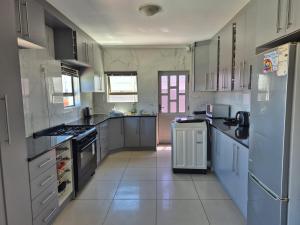 a large kitchen with white cabinets and appliances at Pemba's residence in Cape Town