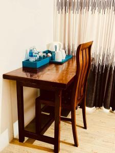 a wooden table with a chair next to a curtain at Atrium Cottage in Seeduwa