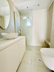 a white bathroom with a sink and a mirror at Holiday Dream Aphrodite Apartment in Mastihari