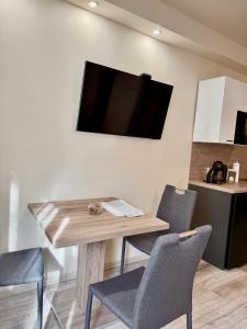 a dining room table with chairs and a television on a wall at AKZ Apartman in Makó +23 photos