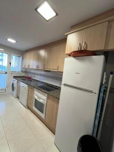 a kitchen with a white refrigerator and wooden cabinets at Appartement Stella vue mer in Piles