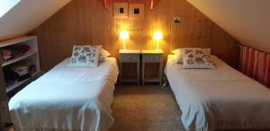 a attic room with two beds and two lamps at La maison bois in Chaon