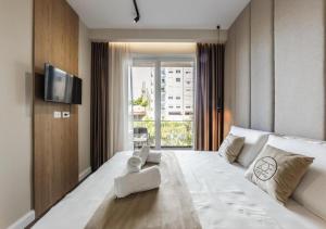 a hotel room with a large white bed and a television at Zoe's Villa by PS in Durrës