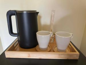 a black pitcher and two cups on a wooden tray at RV3 TRANSIENT HOUSE in Angeles