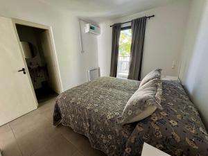 a bedroom with a bed with a blanket and a window at NUX Tandil in Tandil