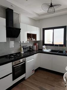 a kitchen with white cabinets and black counter tops at Apartment cosy in Sidi Daoud