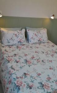 a bed with a floral blanket and two pillows at Garden House Canastra in Delfinópolis