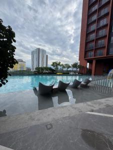 a pool of water with chairs in front of a building at Piccadilly Greentown Ipoh by Jun - City Views in Ipoh