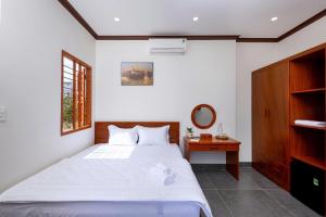 a bedroom with a large white bed and a mirror at Homestay Hòn Đỏ Sea in Thôn Mỹ Tường
