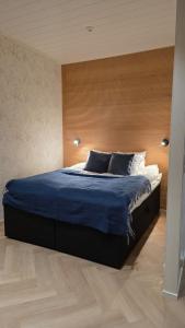 a bedroom with a blue bed with a wooden headboard at Studio Siivilla in Uusikaupunki