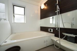 a white bathroom with a tub and a sink at ISE Resort 綾 UZ1 in Ise