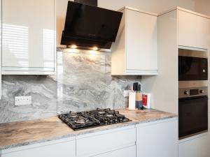 a kitchen with white cabinets and a stove top oven at Liquorstane - Uk40568 in Falkland +12 photos
