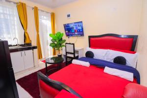 a bedroom with a red bed and a kitchen at The Haven in Nyeri +1 photo
