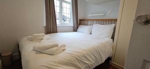 a white bed with towels on it in a room at Spacious Home Near Wembley, Free Parking, Close to Tube, Garden in Pinner
