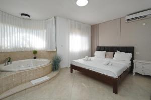 a bedroom with a large bed and a bath tub at Private jacuzzi suite rosh pina in Rosh Pinna