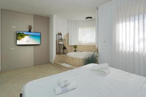 a white bedroom with a bath tub and a bed at Private jacuzzi suite rosh pina in Rosh Pinna