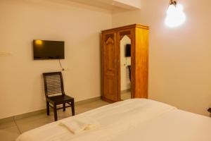 a bedroom with a bed and a chair and a mirror at Jotham Gardens in Alleppey