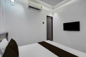 a bedroom with a bed and a tv on the wall at Hotel O Royal Fourtune in Surat