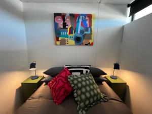 a bedroom with a bed with pillows and a painting at The Happy Chameleon in George +12 photos