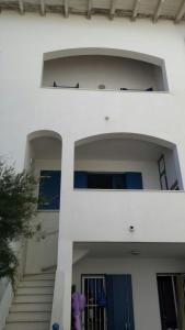a white building with stairs and a blue door at Midnight sun pomposa lido in Lido di Pomposa +2 photos