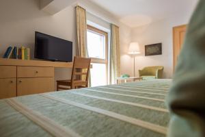 a bedroom with a bed and a tv and a window at Hotel garni Kranzbichlhof in Dürrnberg