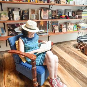 a woman sitting in a chair reading a book at La pequeña casa in Pijao