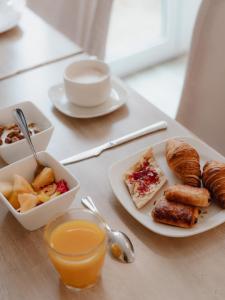 a table with a plate of breakfast foods and a glass of orange juice at Grand Hôtel des Bains SPA in Fouras