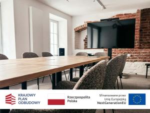 a conference room with a table with chairs and a large screen at Hotel Czarna Róża in Toruń