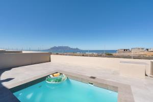 a swimming pool on the roof of a building at Elegant Beach front Villa in Bloubergstrand