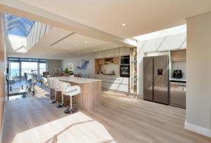 a kitchen with a large island with white stools at Elegant Beach front Villa in Bloubergstrand