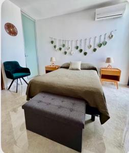 a bedroom with a bed and a green chair at Departamento en Mérida en Privada con Amenidades in Xcanatún +13 photos