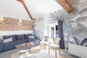a living room with a blue couch and a palm mural at On dirait le Sud - Proche Mâcon SOLEIDOR in Mâcon