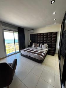 a bedroom with a large bed and a large window at Fnideq Seaside Apartment in Fnidek
