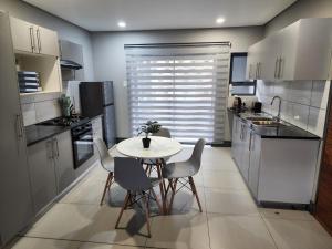a kitchen with a white table and chairs in it at Leaf Mbabane CBD Apartment in Mbabane