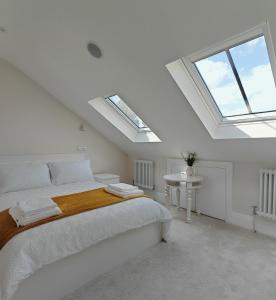 a white bedroom with a bed and skylights at The Windsor Courtyard in Windsor