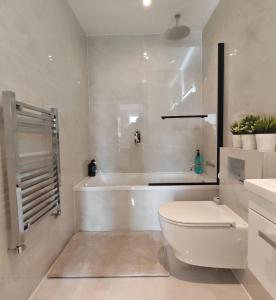 a white bathroom with a toilet and a bath tub at The Windsor Courtyard in Windsor +87 photos