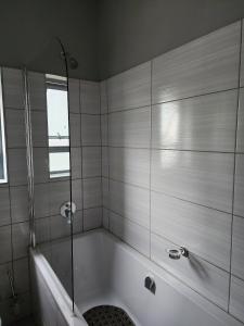 a bathroom with a bath tub with a glass shower at Leaf Mbabane CBD Apartment in Mbabane