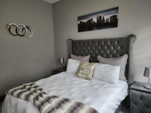 a bedroom with a large bed with white sheets and pillows at Leaf Mbabane CBD Apartment in Mbabane