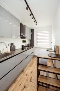 a kitchen with white cabinets and a wooden floor at Kolbi Signature Platinum Residence in Białogard
