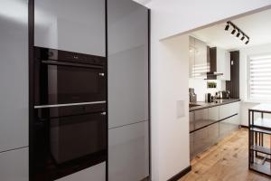 a kitchen with white cabinets and a black refrigerator at Kolbi Signature Platinum Residence in Białogard