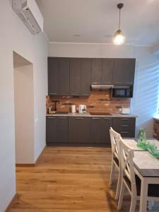a kitchen with black cabinets and a table with chairs at Jūras ielas apartamenti in Limbaži