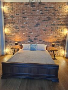 a large bed in a room with a brick wall at Jūras ielas apartamenti in Limbaži