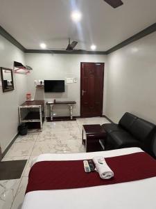 a room with a bed and a couch and a tv at Serenity Sunrise Beach Resort in Pondicherry