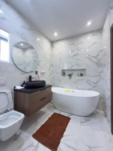 a white bathroom with a tub and a sink at Luxury Executive Balcony Suite at THE HIDDEN DOMUS I Elmina Suite in Accra +18 photos