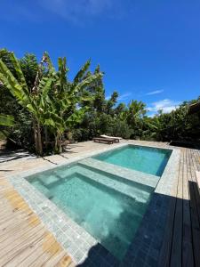 a swimming pool next to a wooden deck at MAHAGUA Casa Holística - Jambreiro, Caraiva, BA in Porto Seguro