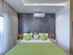 a bedroom with a large bed with green pillows at Luxury Executive Balcony Suite at THE HIDDEN DOMUS I Elmina Suite in Accra