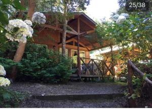 a log cabin with a wooden porch and flowers at Cabañas el Bosque Patagónico in Frutillar